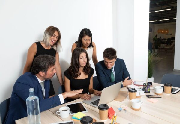Manager training two employees on a production whiteboard; focused team communication and coaching session for a future supervisor.