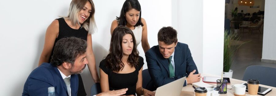 Manager training two employees on a production whiteboard; focused team communication and coaching session for a future supervisor.